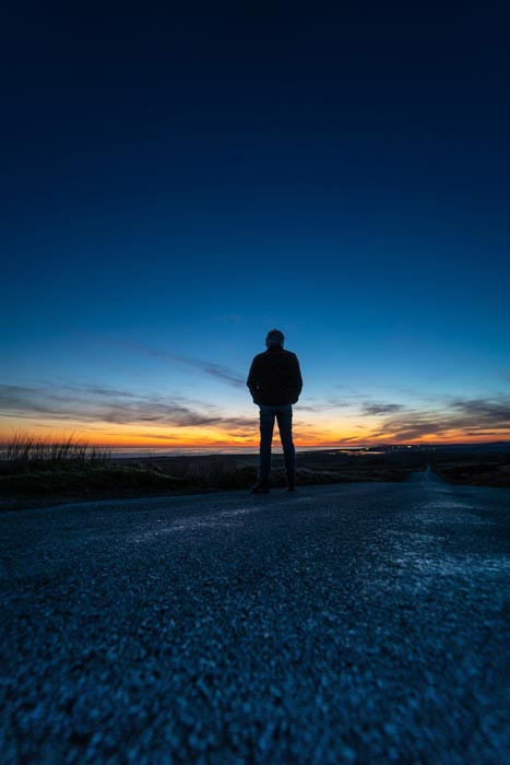 Person standing on road at sunset